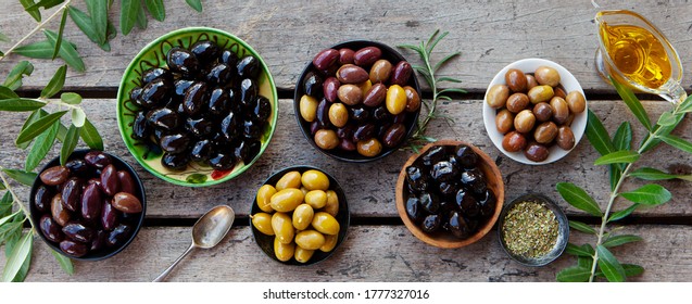 Assortment of fresh olives on a plate with olive tree brunches. Wooden background. Top view. - Powered by Shutterstock