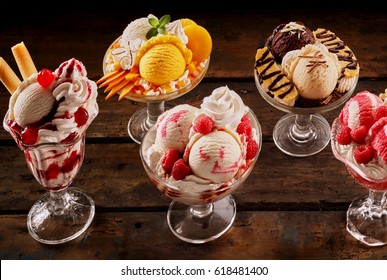 Assortment of fruity ice-cream sundae desserts made of artisanal Italian gelato garnished with cream and fresh, strawberries, raspberries, mango, pineapple, banana and cherries