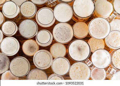 An Assortment Of Full, Frothy Beer Glasses And Sizes On A Bar Bench Top.