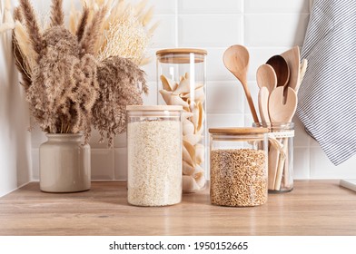 Assortment of grains, cereals and pasta in glass jars and kitchen utensils on wooden table - Powered by Shutterstock