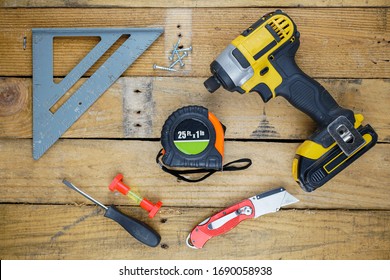 Assortment of hand tools spread out on rough wooden background. 