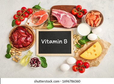 Sortiment an Vitamin B-Quellen auf weißem Hintergrund: Milch, Leber, Olivenöl, Tomaten, Garnelen, Erdnüsse, Rindfleisch, Spinat, Lachs, Keshew, Käse, Eier, Haricot. Draufsicht.