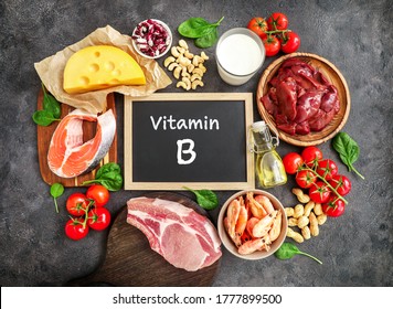 Assortment of high vitamin B sources on dark background: milk, liver, olive oil, tomatoes, prawns, peanuts, beef, spinach, salmon, keshew, cheese, haricot. Top view.