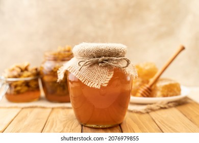 Assortment of honey products: honeycombs, nuts in honey, beeswax in table. Healthy organic honey dipping in jar, closeup. Honey pouring in glass bowl - Shutterstock ID 2076979855