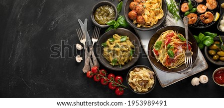 Assortment of Italian pasta with traditional sauces for dinner on dark background. Homemade food concept. Top view