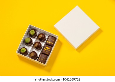 Assortment Of Luxury Bonbons In Box On Bright Yellow Background. Exclusive Handmade Chocolate Candy. Minimal Food Concept 