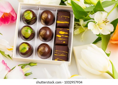 Assortment Of Luxury Bonbons In Gift Box On White Background With Flowers. Exclusive Handmade Chocolate Candy. Springtime, Womans Day, Valentines Day Concept