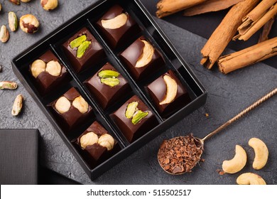 Assortment of luxury handmade chocolate candy with nuts in a gift box on black background. Exclusive bonbons with cashew, pistachios and hazelnuts