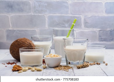 Assortment of non dairy vegan milk and ingredients on white wooden background. Healthy drinks concept. Copy space