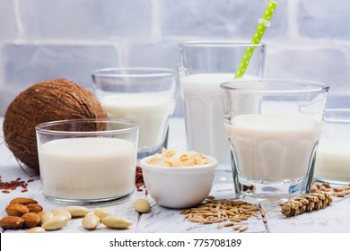 Assortment of non dairy vegan milk and ingredients on white wooden background. Healthy drinks concept. Copy space