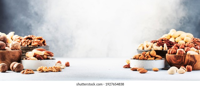 Assortment of nuts in bowls. Cashews, hazelnuts, walnuts, pistachios, pecans, pine nuts, peanuts, macadamia, almonds, brazil nuts. Food mix on gray background, copy space banner  - Shutterstock ID 1927654838