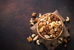 Assortment Of Nuts In Wooden Bowl On Dark Stone Table. Cashew, Hazelnuts, Walnuts, Almonds, Brazilian Nuts And Pine Nuts. Top View With Copy Space.