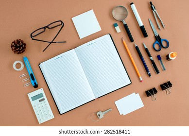 Assortment Of Office Supplies Neatly Organized Around Note Book Open To Blank Page On Desk Top Surface