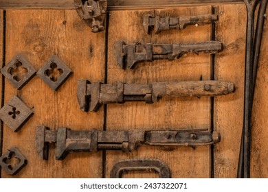 An assortment of old rusty tools hang on a wall. Wrenches and dies.