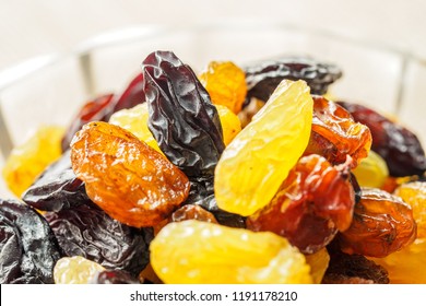 Assortment Of Raisins, Yellow, Blue, Black, Golden Raisin  In Glass Bowl And Wooden Spoon On Kitchen. Healthy Snack, Dietary Product For Good Life. Copy Space, Vega Food. Close-up Image. Macro.