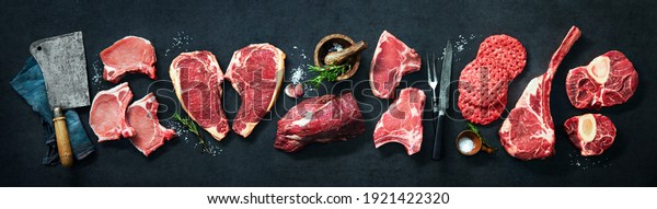 Assortment of raw cuts of meat, dry aged beef\
steaks and hamburger patties for grilling with seasoning and\
utensils on dark rustic\
board