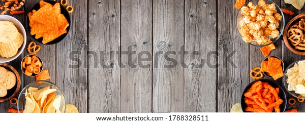 Assortment of salty\
snacks. Double border with copy space. Top view on a rustic wood\
banner background.