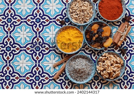 Assortment of spices in bowls on oriental tile background, top view of various Indian herbs and spices, space for text