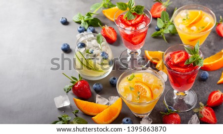 Assortment summer non-alcoholic cocktails with fresh berries, herbs and fruits on dark background.