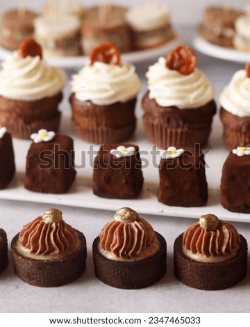 An assortment of sweets featuring banana cupcakes, hazelnut tartlets, and chocolate truffles in cocoa, complemented by savory sandwiches