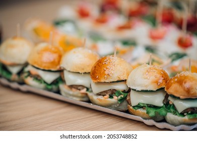 Assortment of tasty appetizers - mini burgers, cheesy canapes, wrap with meat chicken and vegetables, mini snacks with caviar
