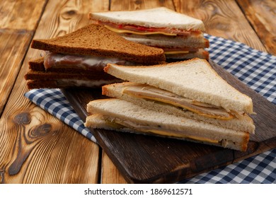 Assortment Of Toasted Triangle Sandwiches On Wooden Board