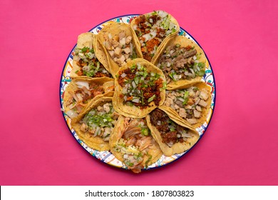 Assortment of traditional mexican tacos on pink background