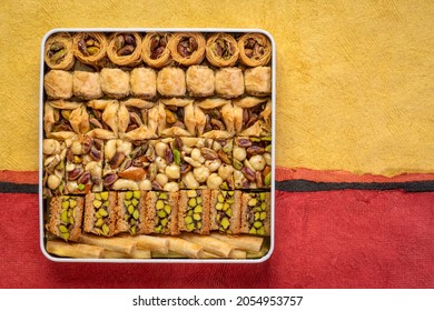 Assortment Of Traditional Turkish Baklava Pastry In A Tin Box, A Dessert Is Well Also Known As Persian Or Lebanese Baklava, Textured Paper Background With A Copy Space