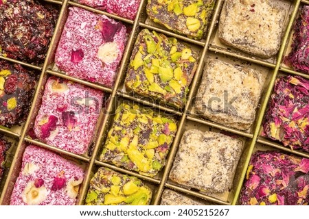 assortment of traditional Turkish delight (lokum) in a tin box against handmade paper with a copy space, soft, juicy, and chewy dessert from the middle east