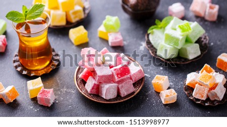 Assortment of Turkish delights with glass of tea. Grey background.
