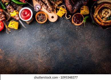 Assortment various barbecue food grill meat, bbq party fest - shish kebab, sausages, grilled meat fillet, fresh vegetables, sauces, spices, dark rusty concrete table, above copy space