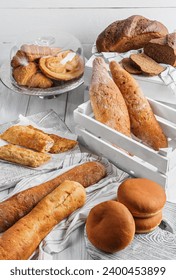 Assortment of various delicious freshly baked bread on white wooden background. Vertuta, stuffed bread, pastries, croissants, strudel, baguette, buns. Homemade healthy bread, grocery store, top view