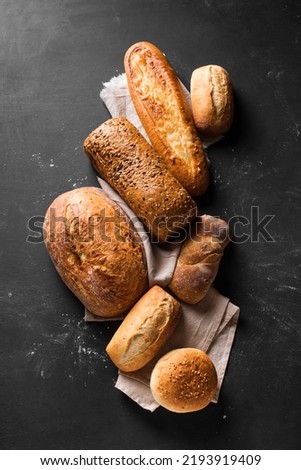 Assortment of various delicious freshly baked bread on black background. Variety of artisan bread composition.