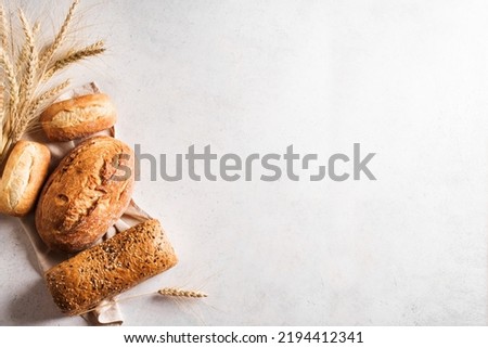 Assortment of various delicious freshly baked bread on white background, copy space. Variety of artisan bread composition and ears of wheat.
