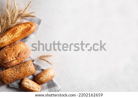 Assortment of various delicious freshly baked bread on white background. Variety of artisan bread composition and ears of wheat.