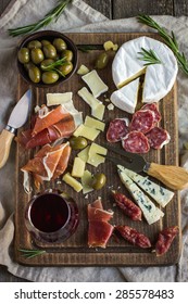 Assortment Of Various Types Of Cheese And Meat On Wooden Board, Top View