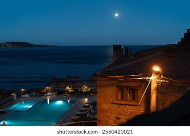 Assos Moonlit Night: Serene Poolside View Overlooking the Aegean Sea with Full Moon and Tranquil Atmosphere. - Powered by Shutterstock