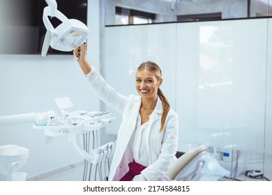 Assure And Beautiful Dental Doctor With Brilliant Healthy Smile All Over Her Face In Front Of Dentist Room. Dental Professional. Portrait Of Female Dentist .She Standing In Her Dentist Office..