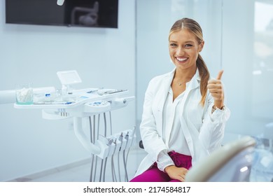 Assure And Beautiful Dental Doctor With Brilliant Healthy Smile All Over Her Face In Front Of Dentist Room. Dental Professional. Portrait Of Female Dentist .She Standing In Her Dentist Office..