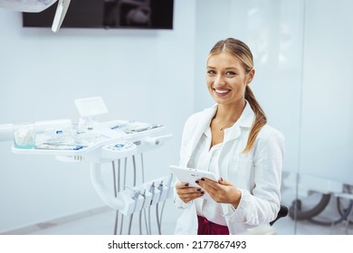 Assure And Beautiful Dental Doctor With Brilliant Healthy Smile All Over Her Face In Front Of Dentist Room. Dental Professional. Portrait Of Female Dentist .She Standing In Her Dentist Office..