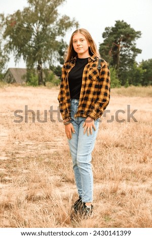 Assured girl outside. Portrait preteen girl on the nature background. Girl 13 years old. Blonde long hair. Attractive teenager. Serious teen girl. Out of focus.