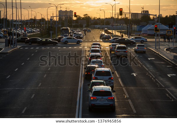 Astana, Kazakhstan - August 19, 2017: Cars in the\
city of Astana at sunset. Auto traffic at sunset during rush hour.\
Закат в городе астана, нур-султан, трафик авто в городе на закате,\
красивые фары