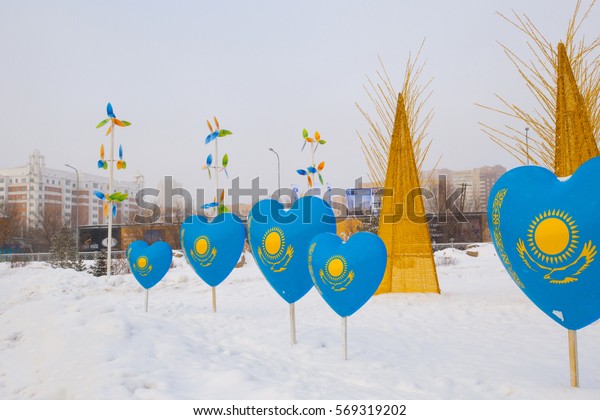 Astana,\
Kazakhstan - January 15, 2017: Plastic models in the form of hearts\
with the image of the flag of Kazakhstan. On the ground is snow, in\
the background drive cars, people\
walking.
