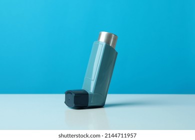 Asthma Inhaler On White Table Against Blue Background