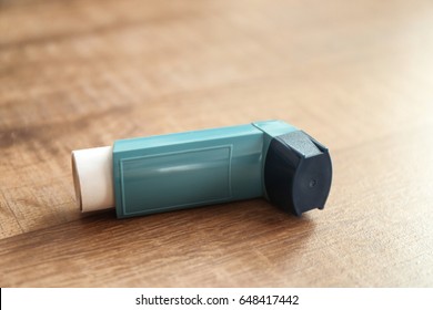 Asthma Inhaler On Wooden Table