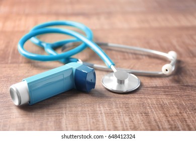 Asthma Inhaler With Stethoscope On Wooden Table