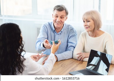 Asthma Treatment. Female Doctor Giving Blue Inhaler To Senior Patient Who Is Sitting With His Mature Wife, Copyspace