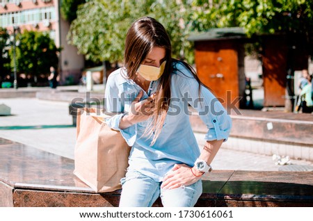 Asthmatic Female with Respiratory problem resting in the city street. Woman with madical protective mask out of breath,holding hand on chest.Young Woman with breathing pain in lungs