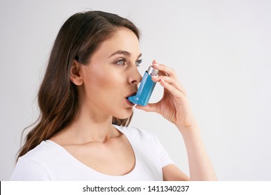 Asthmatische Frau, die während eines Asthmaanfalls ein Asthma-Inhalationsgerät verwendet 