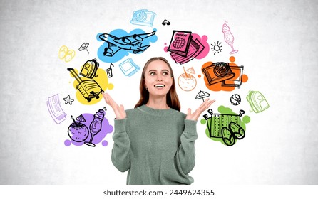 Astonished and happy woman portrait with raised hands, different travel icons doodle sketch on grey concrete wall background. Suitcase, airplane, camera and passport. Concept of trip to dream